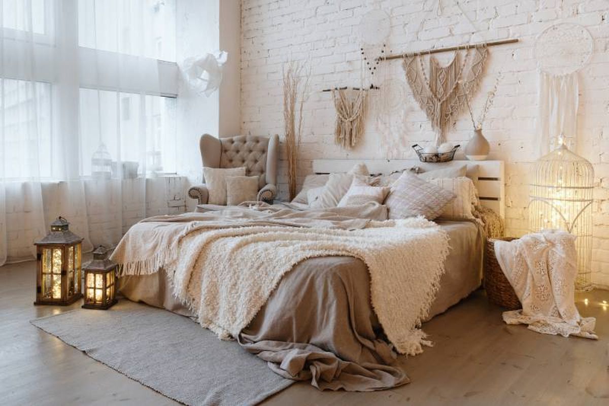 Dormitorio de estilo boho moderno con sábanas marrones y manta beige.