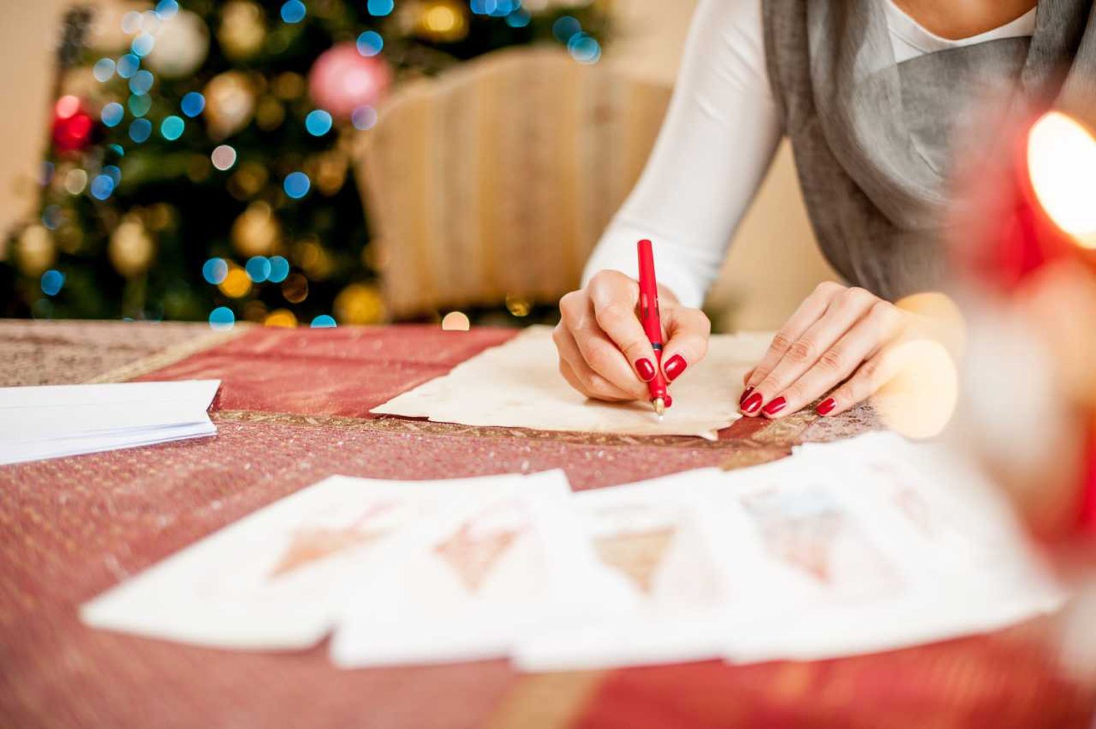 Mujer escribiendo una postal navideña.