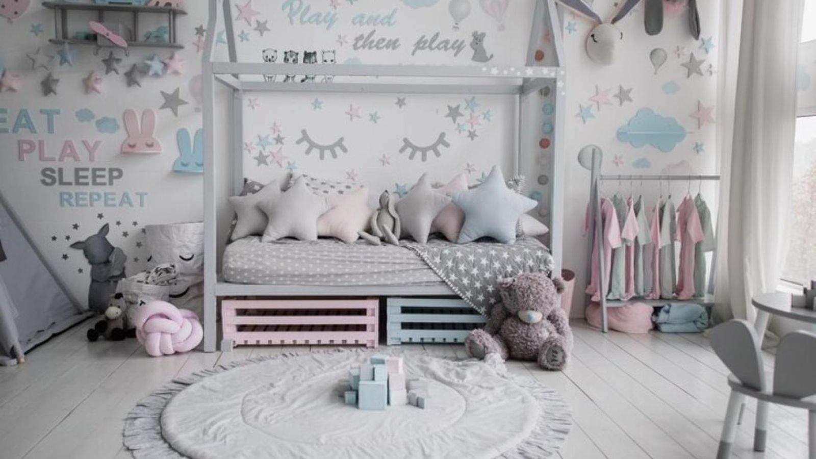 Habitación infantil con cama tipo casita decorada en gris, rosa y azul.