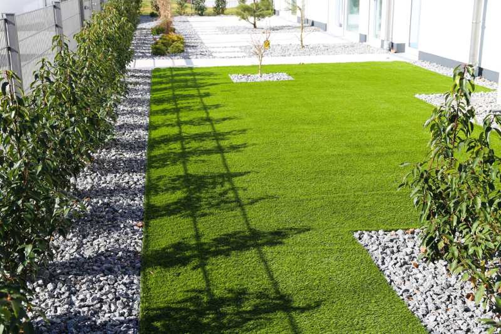 Patio con césped artificial y piedras.