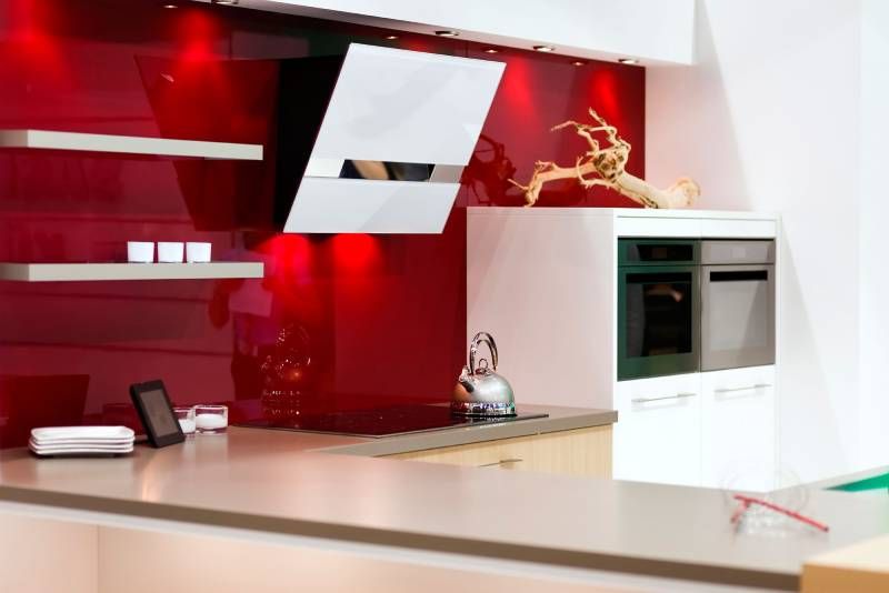 Cocina con pared en color rojo decorada con muebles blancos.