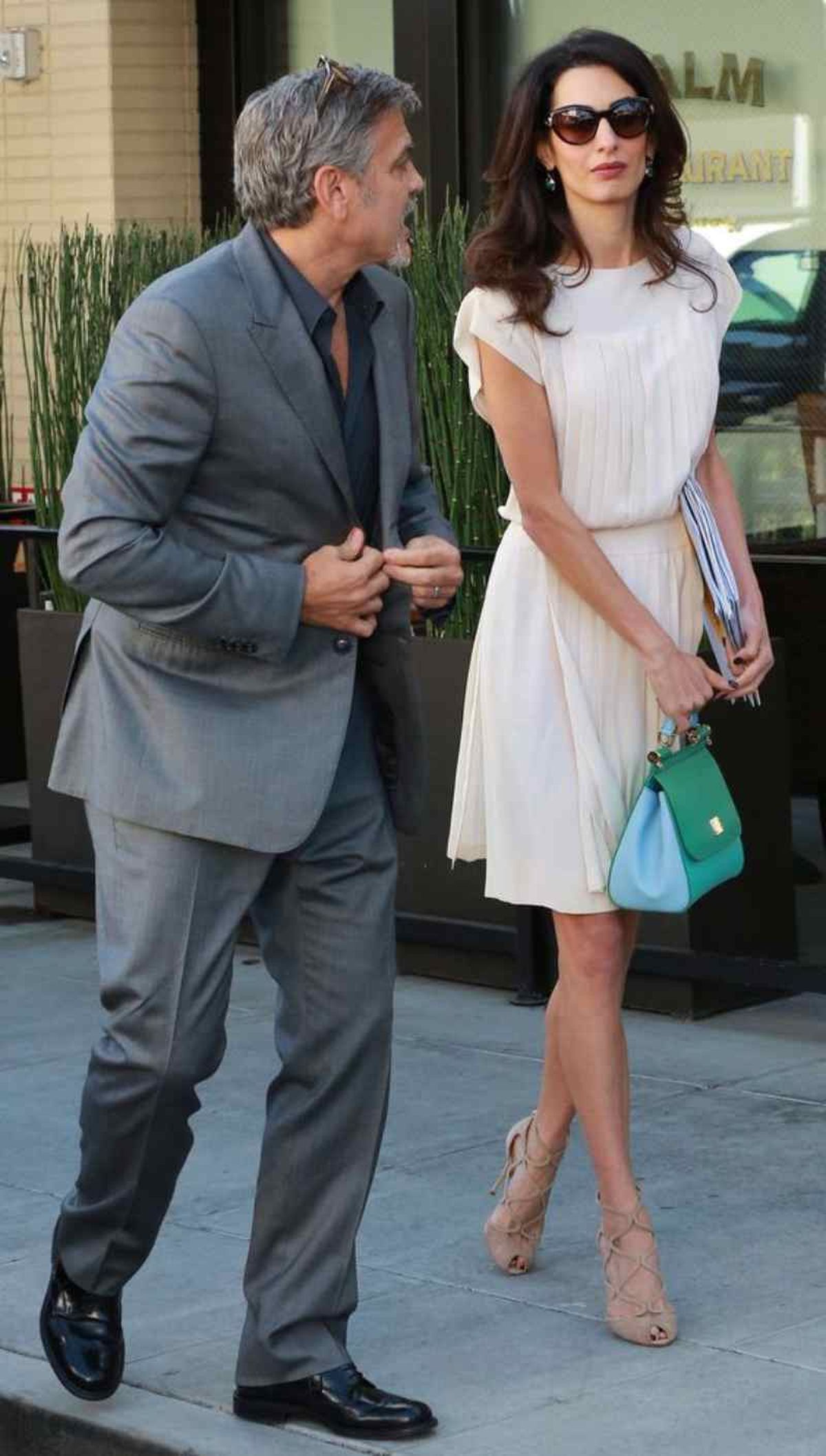 Amal Clooney con vestido y zapatos nude y bolso en tonos azules y verdes