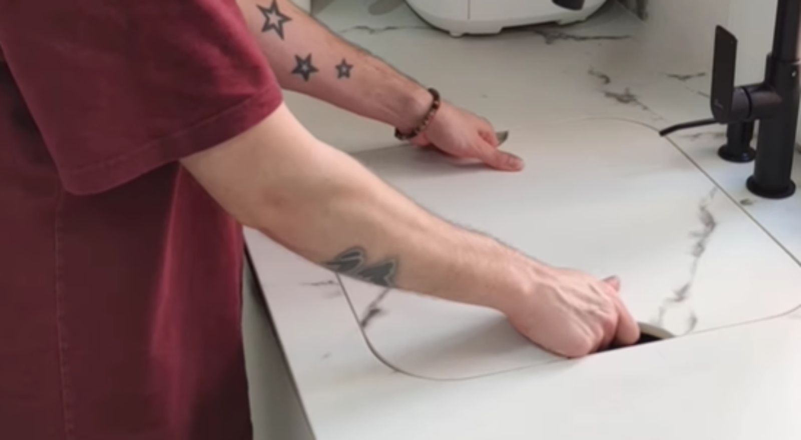 El influencer Omar Díaz junto el su cocina colocando la tapa a su fregadero oculto.