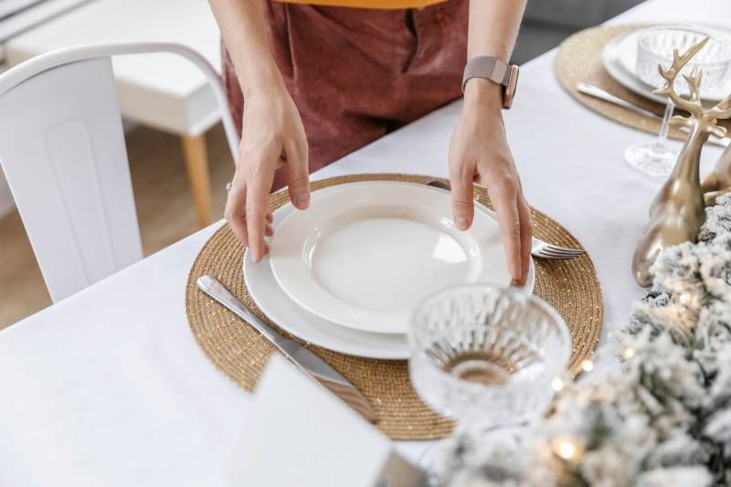 Mesa con decoración navideña blanca y dorada.
