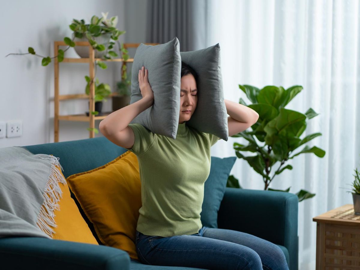 Mujer tapándose los oídos con cojines.