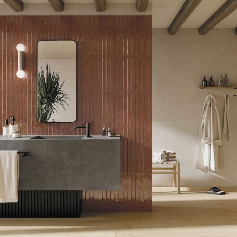 Baño con azulejos marrones alargados.