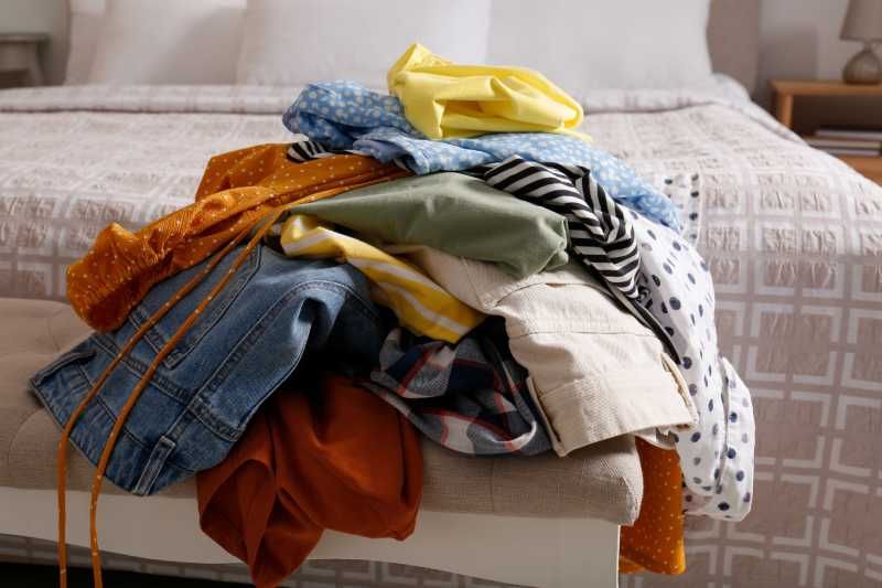 Montaña de ropa desordenada sobre la cama.