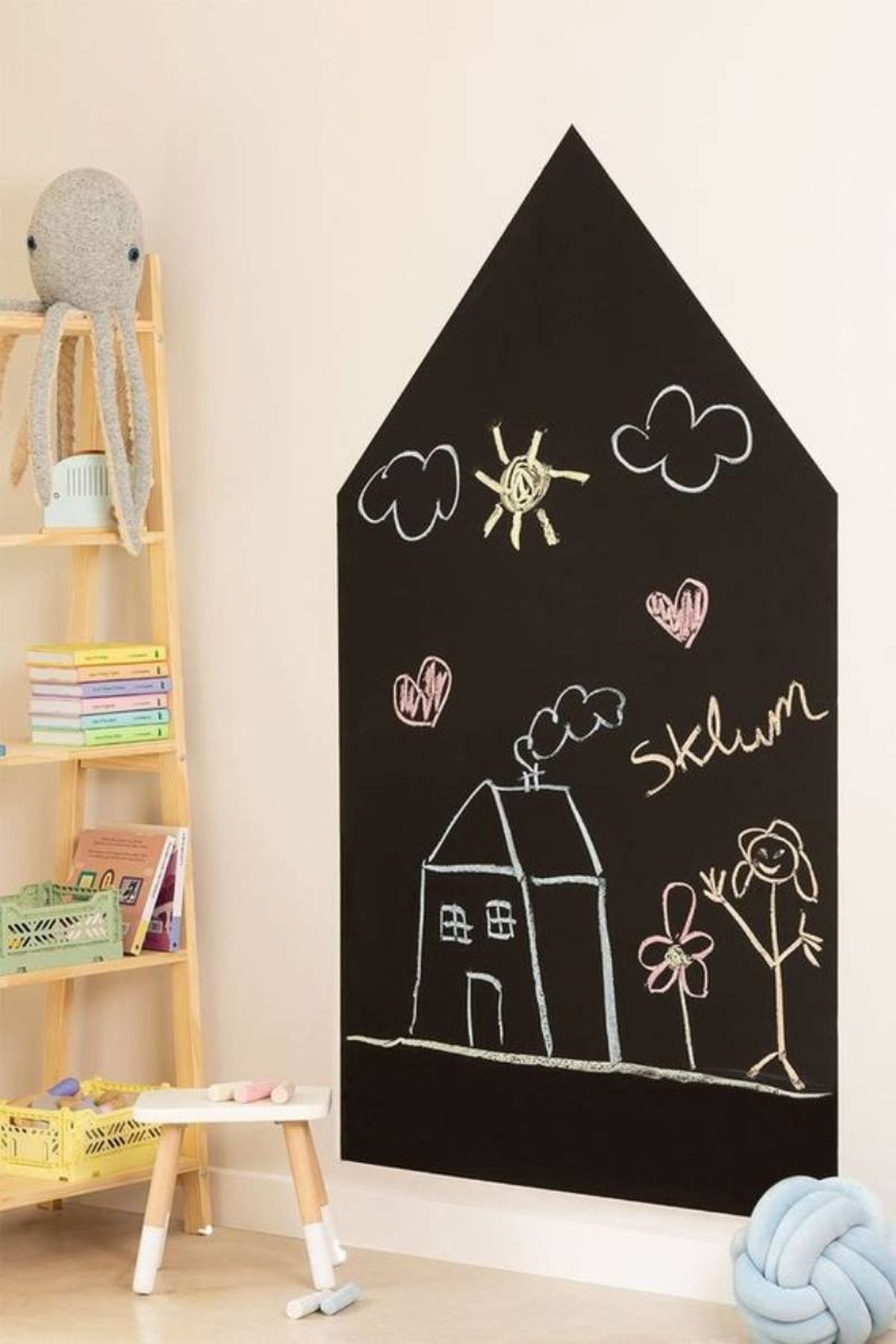 Pizarra con forma de casita en la pared.
