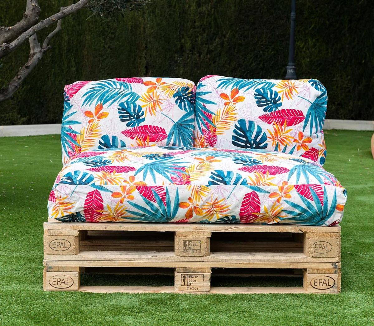 Sofá hecho con palets con cojines coloridos con estampado tropical.