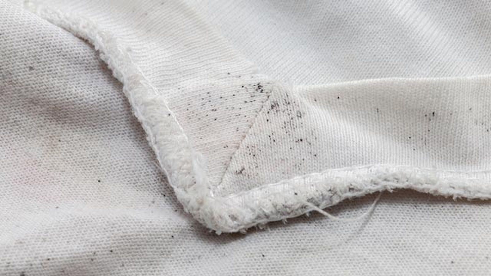 Camiseta blanca con manchas moho o humedad (puntitos negros)
