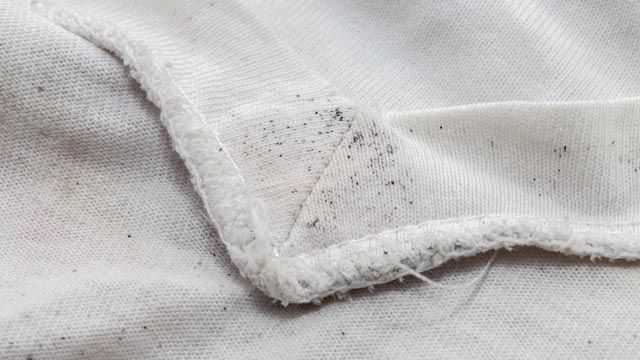 Camiseta blanca con manchas moho o humedad (puntitos negros)