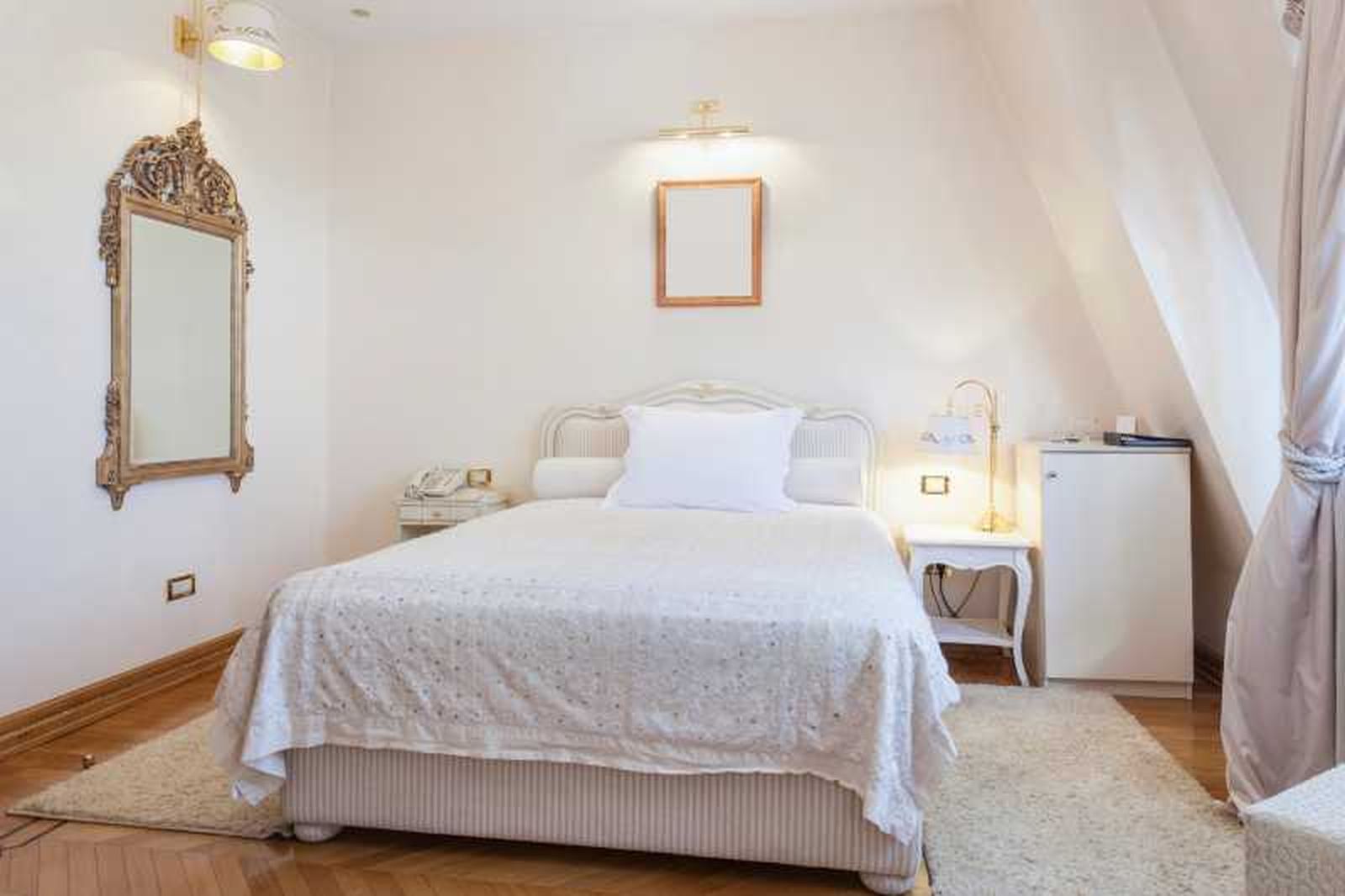 Dormitorio pequeño decorado con un espejo barroco.