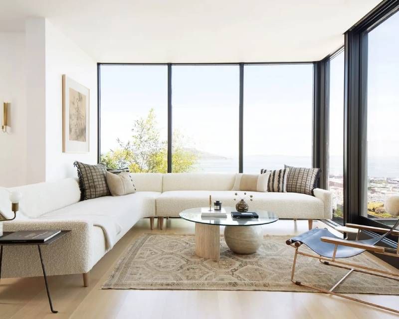 Salón con ventanal decorado en tonos claros y de estilo minimalista.