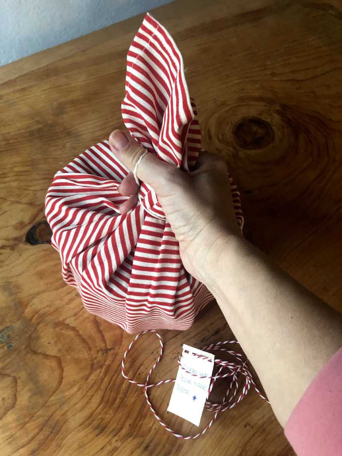 Paso dos para envolver una caja de galletas con tela furoshiki.