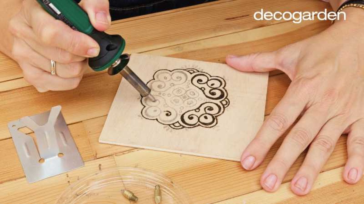 Grabar el diseño de mandala con el pirógrafo sobre una pequeña madera.