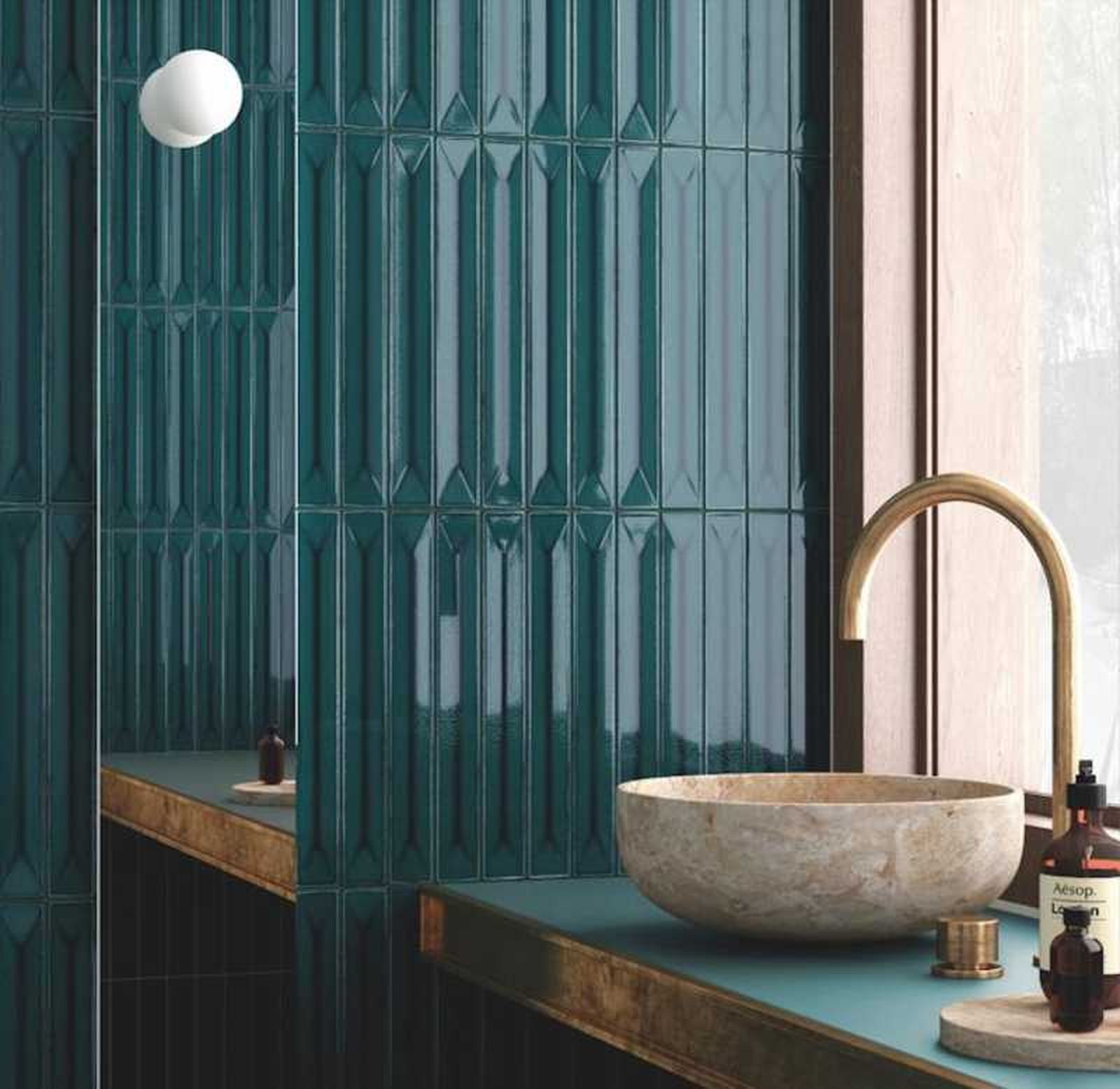 Baño con lavabo de piedra y azulejos verdes en la pared.