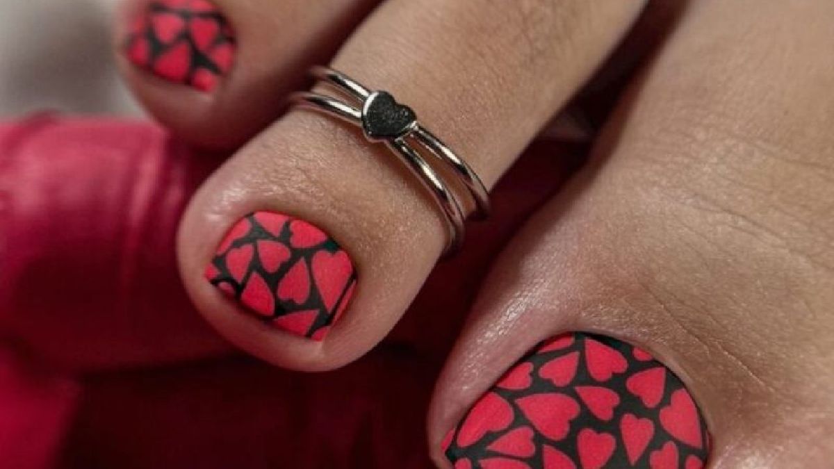 Pedicura con corazones rojos sobre fondo negro