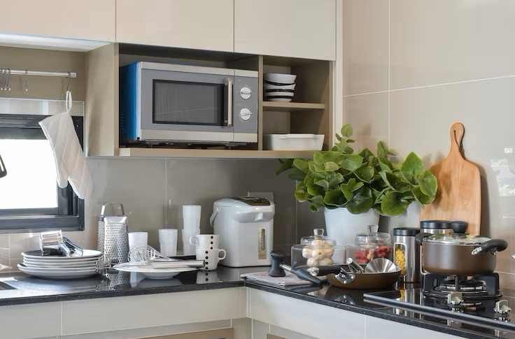 Microondas suspendido debajo de los muebles altos de la cocina.