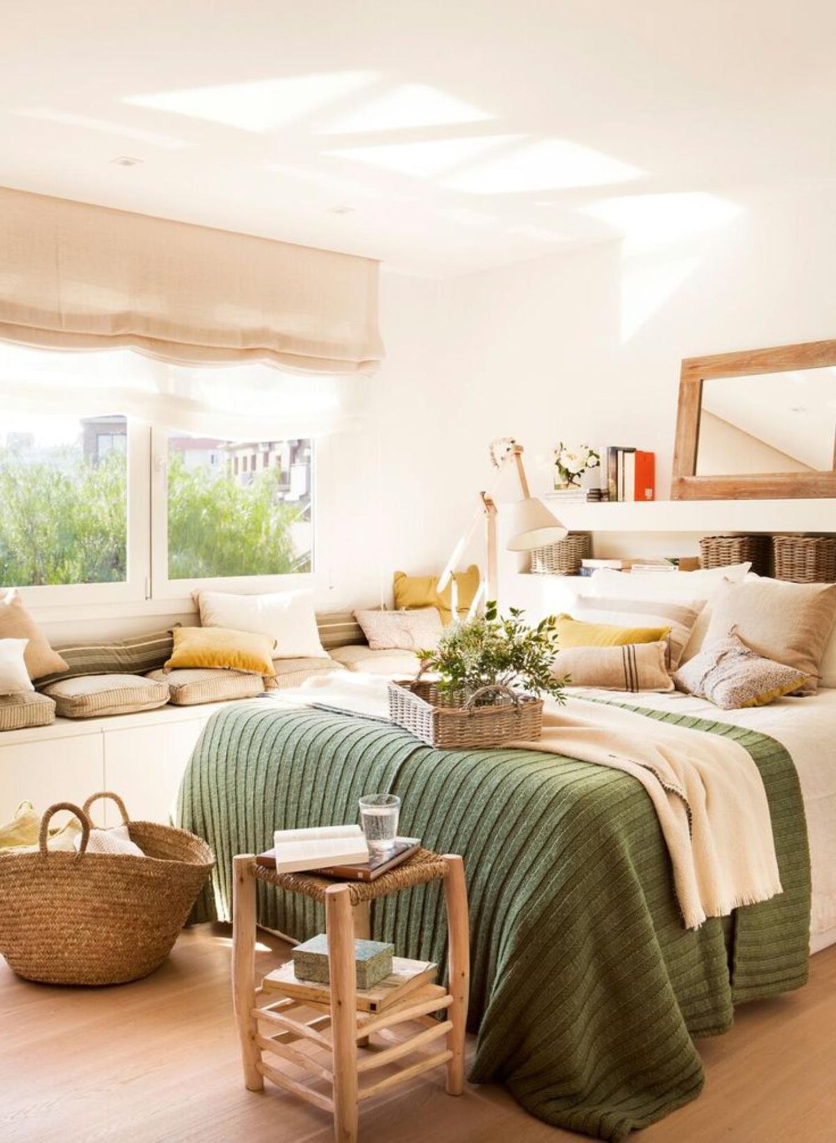 Dormitorio con una banqueta y una cesta a los pies de la cama.