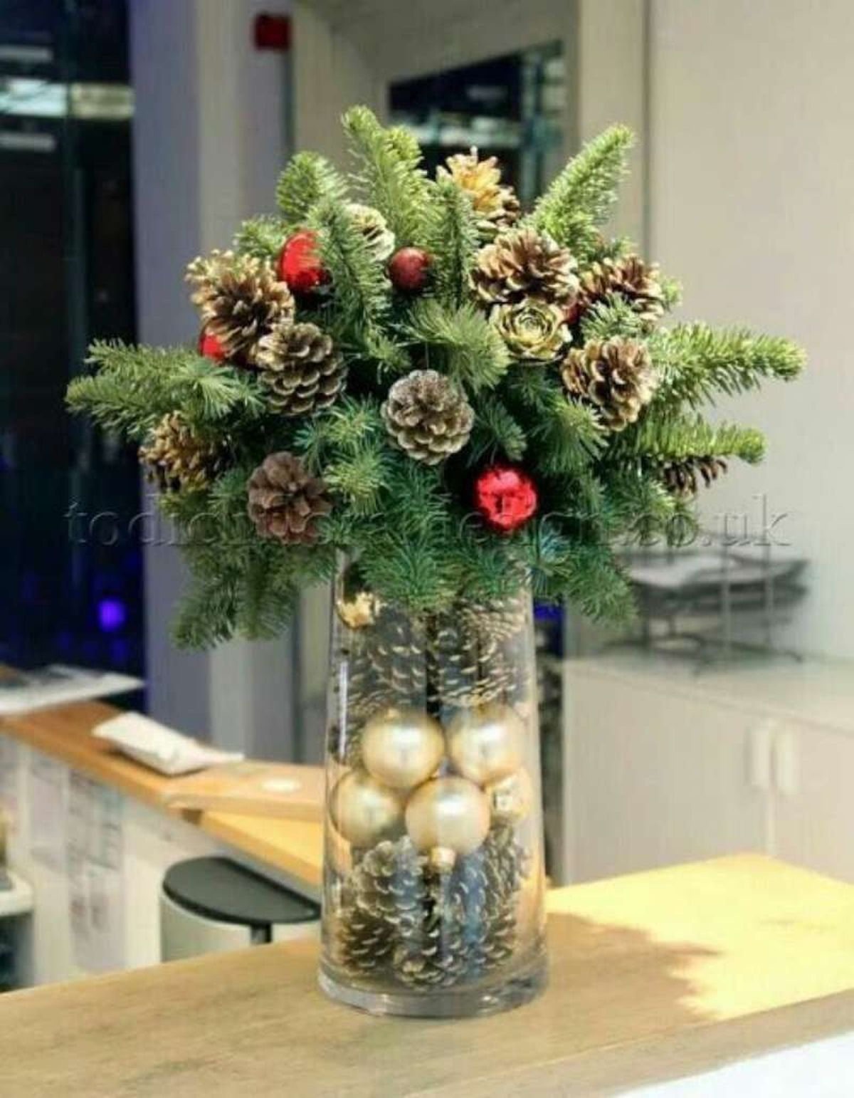 Jarrón de Navidad decorado con piñas secas y bolas.
