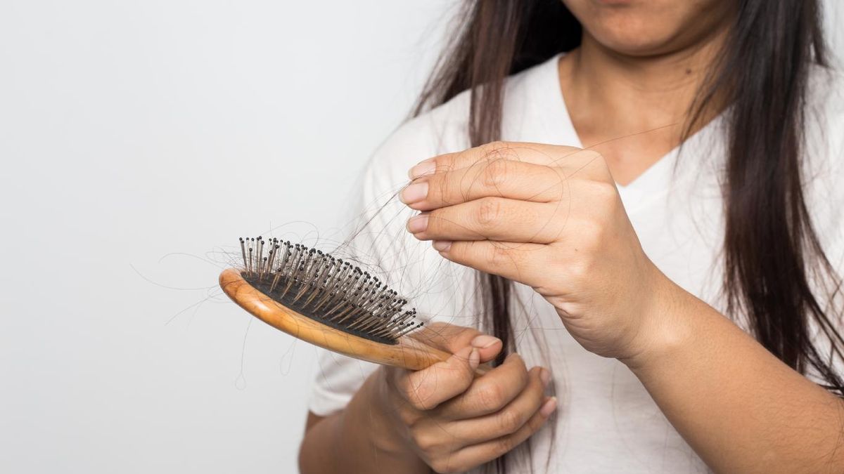Mujer quitando los pelos del cepillo para el cabello.
