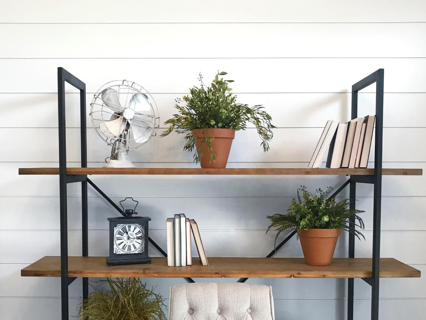 Estantería metálica con plantas y decoración.