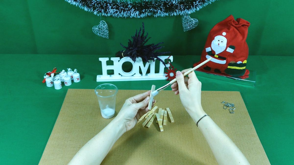 Paso dos para hacer estrellas de Navidad con pinzas de madera.