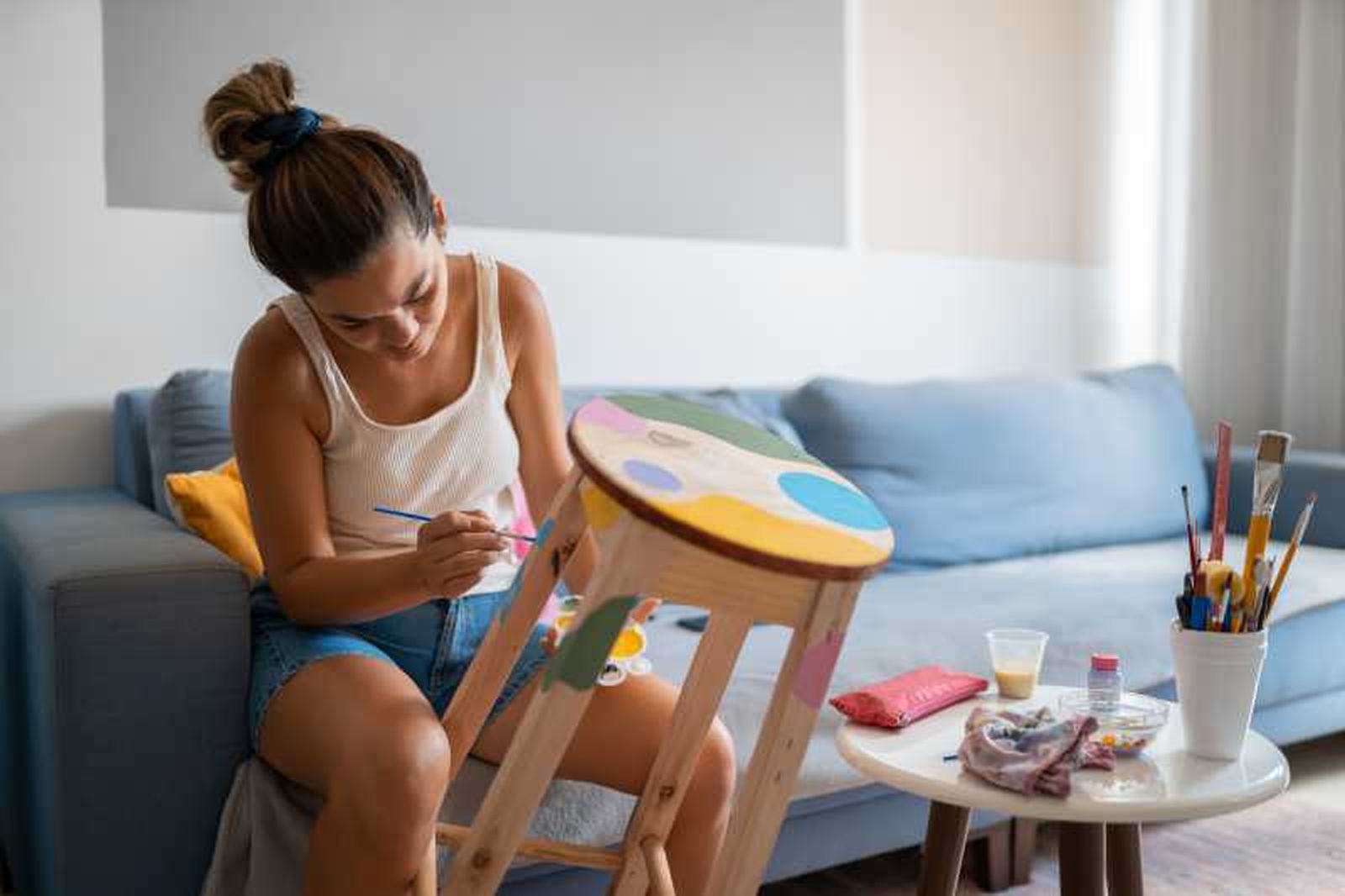 Mujer pintando una banqueta de colores.