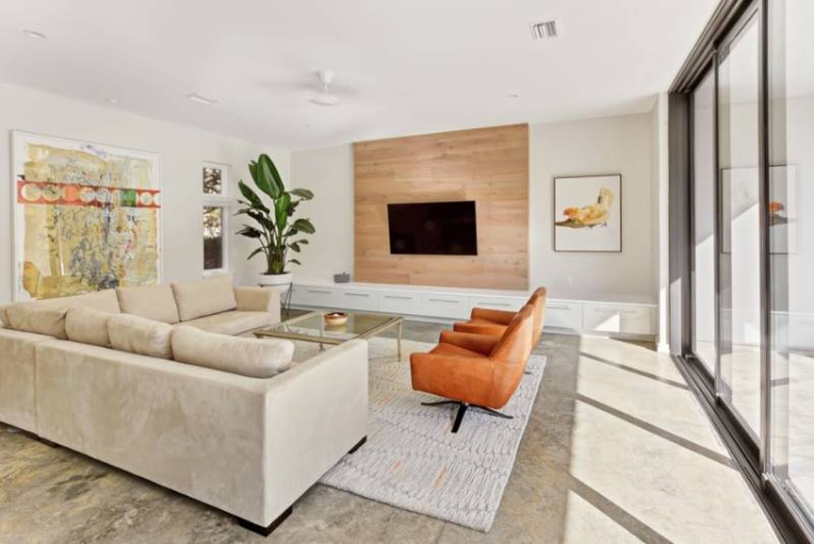 Salón de una casa minimalista en tonos claros con butaca naranja.