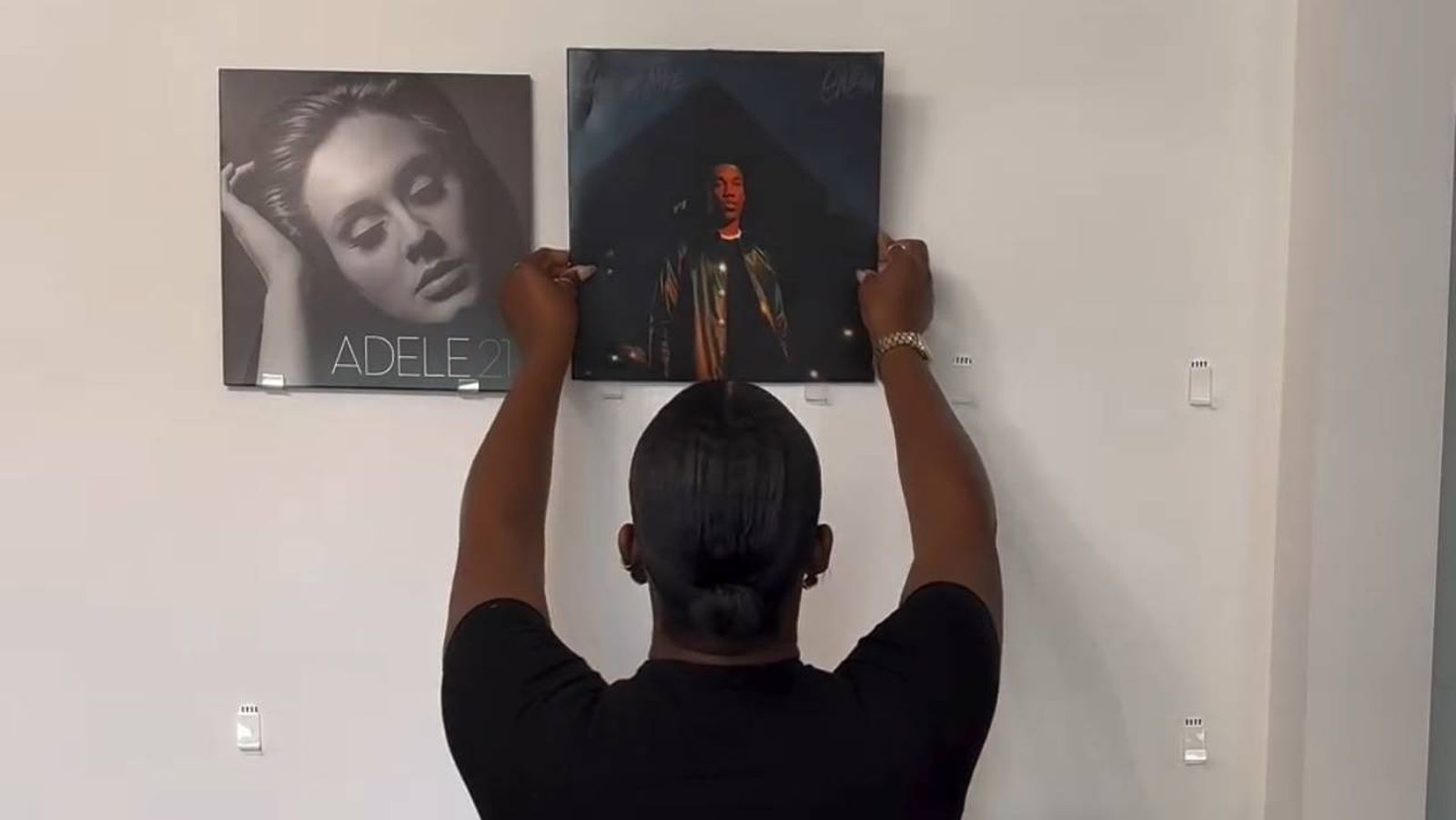 Maya Galore colocando unos vinilos de música en la pared para decorar.