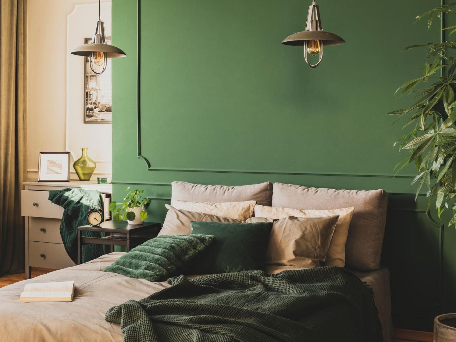 Dormitorio con textiles beiges y pared verde.