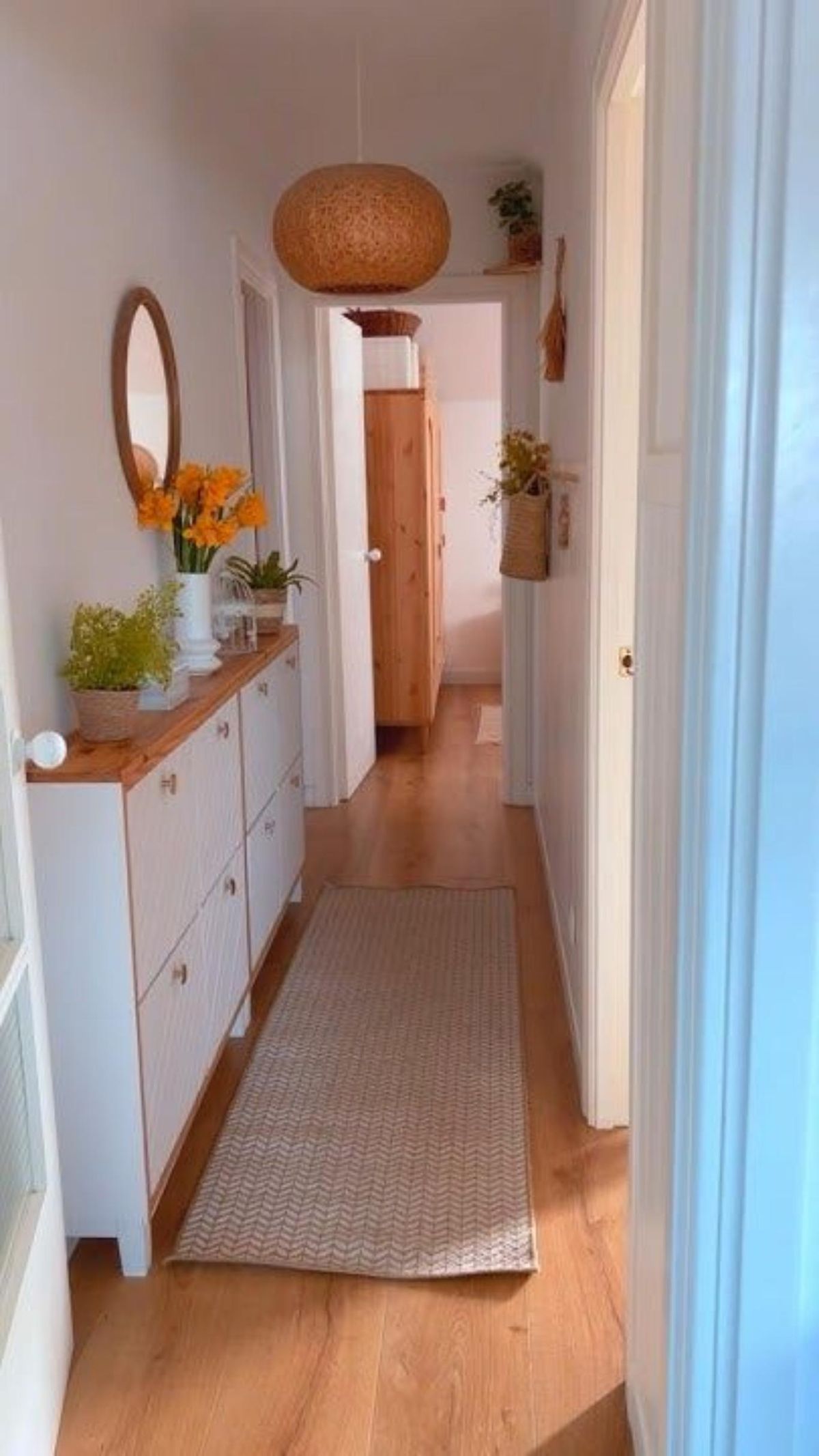 Pasillo largo con muebles estrechos y complementos decorativos.