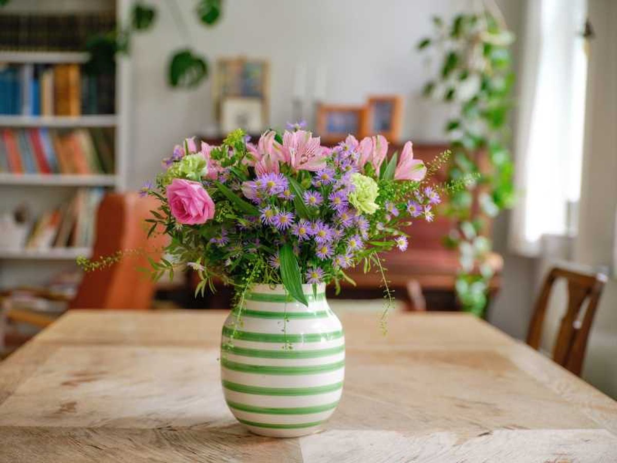 Jarrón de flores con un ramo encima de la mesa.