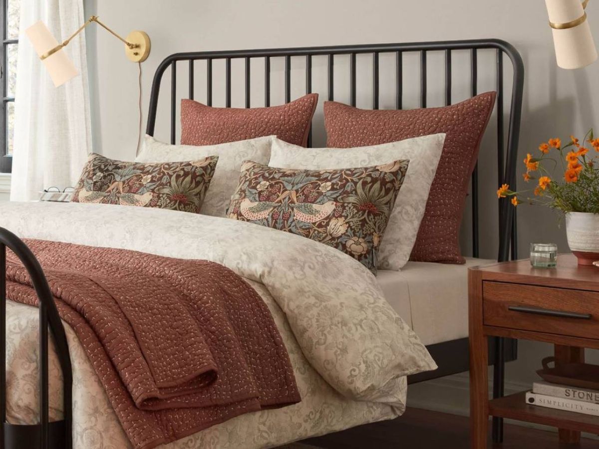 Textiles con carácter para un cabecero de forja negra que destaca en un dormitorio elegante.