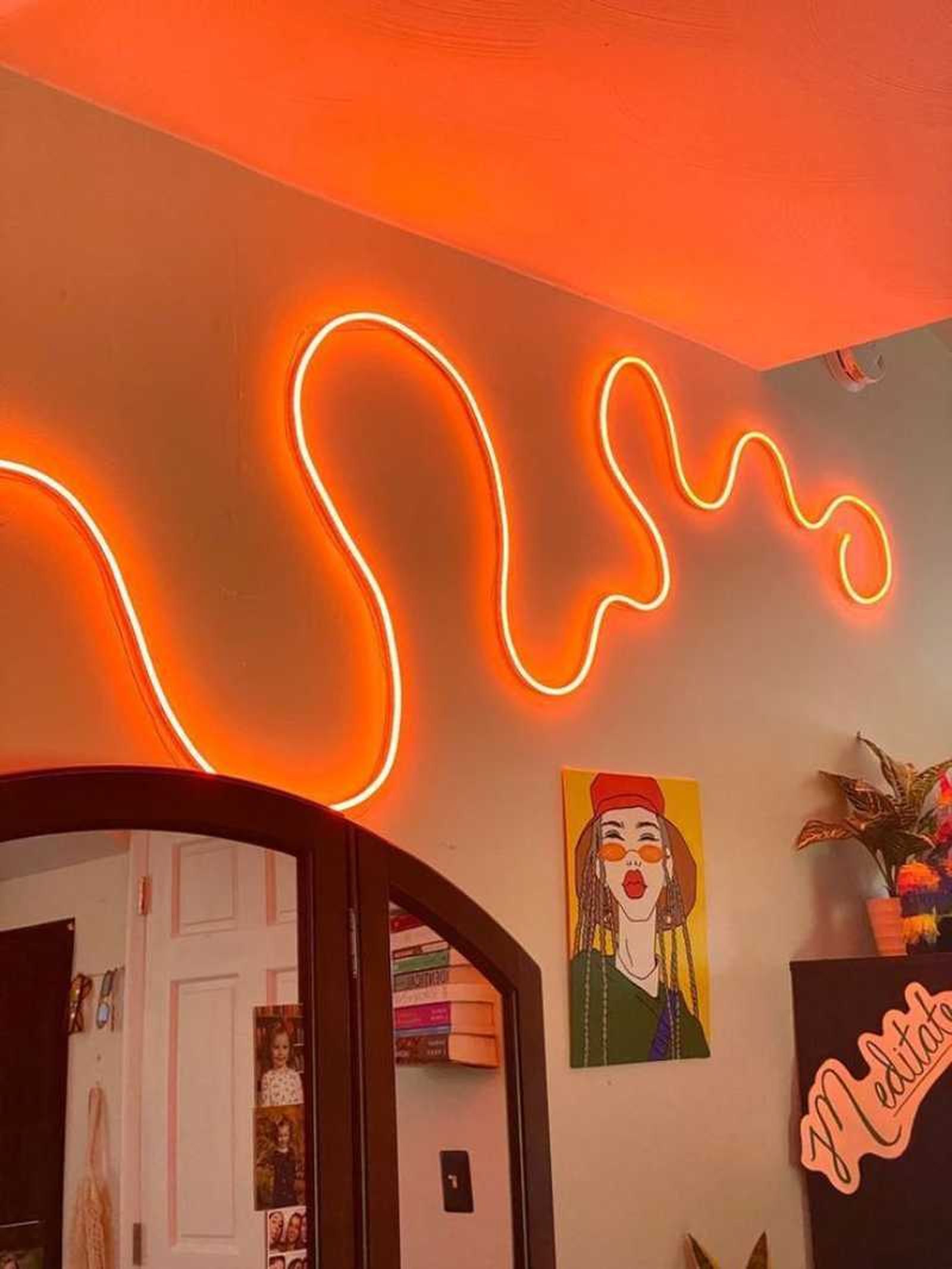 Dormitorio juvenil con luces de neón por la pared.