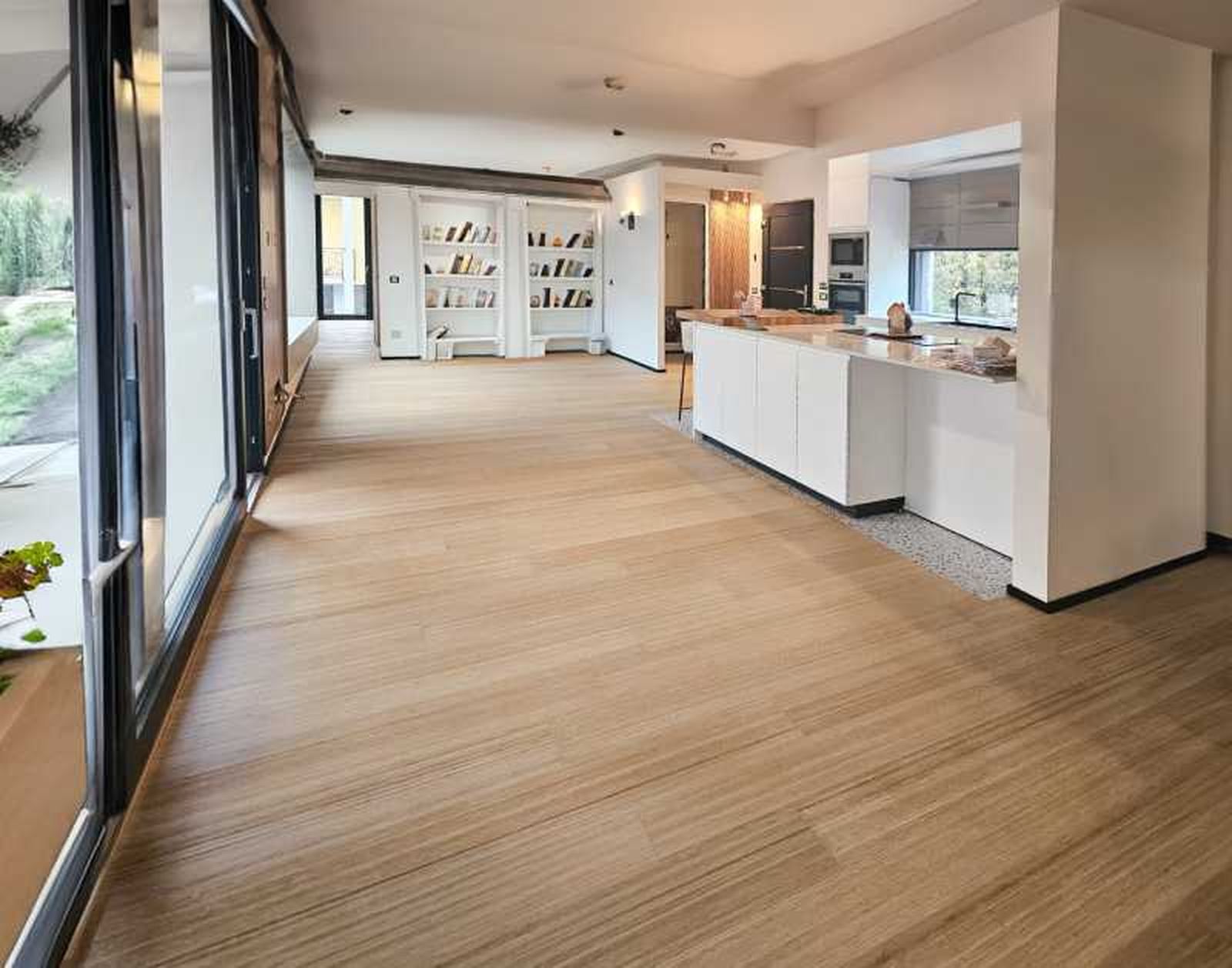 Cocina abierta con suelo de madera clara.