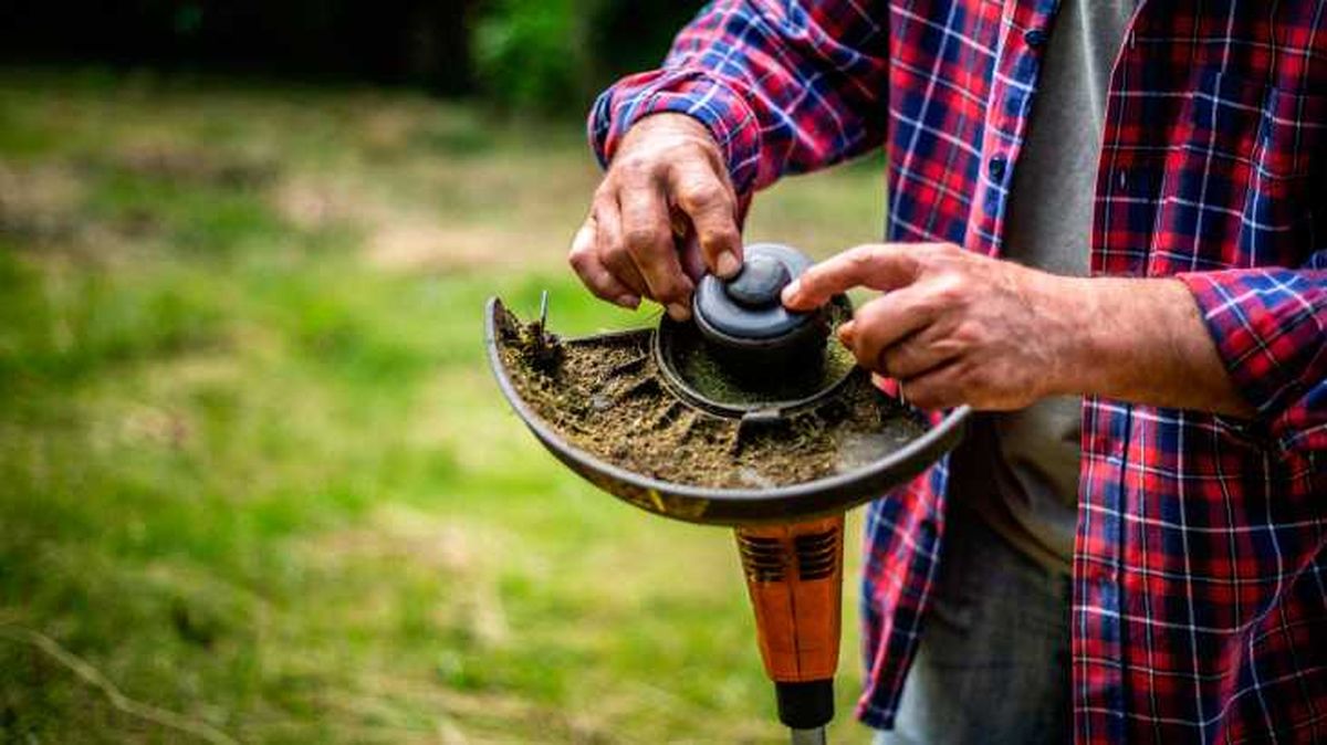 Persona sustituyendo el hilo de la desbrozadora