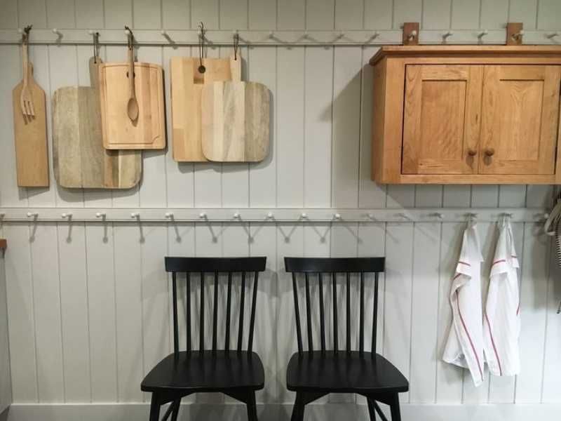 Cocina de estilo shaker con sillas negras y tabla de madera.