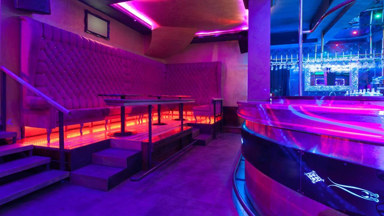 Discoteca pequeña con luces con luces de neón moradas y rojas.