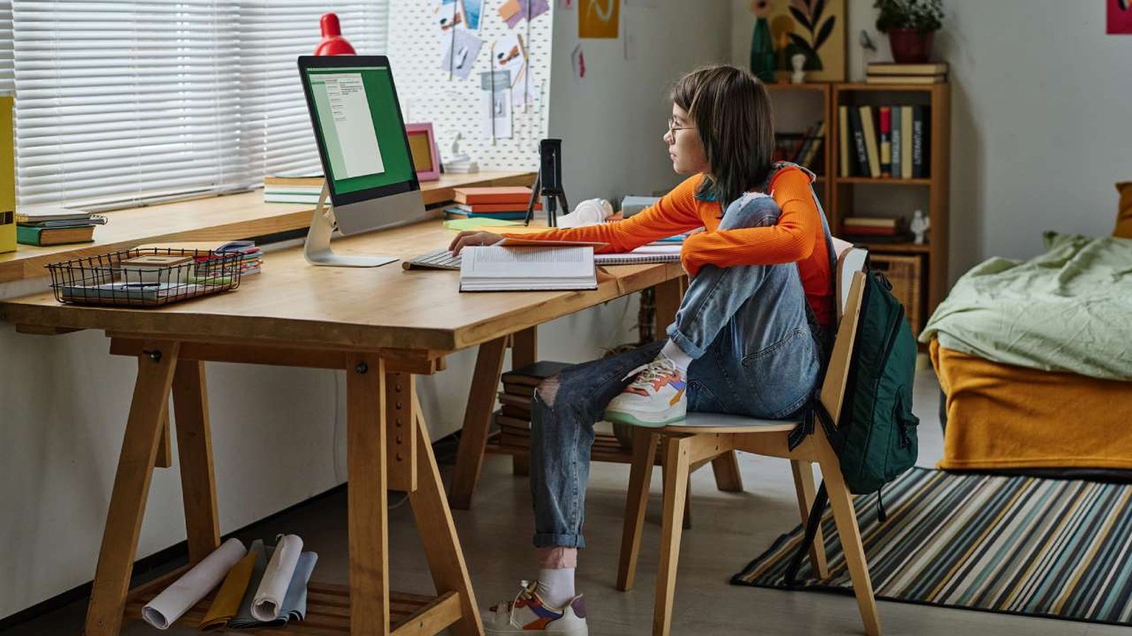Adolescente sentada en el escritorio de su habitación.