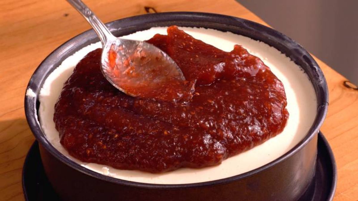 Añade mermelada de fresa sobre la tarta de queso para realzar su sabor y presentación