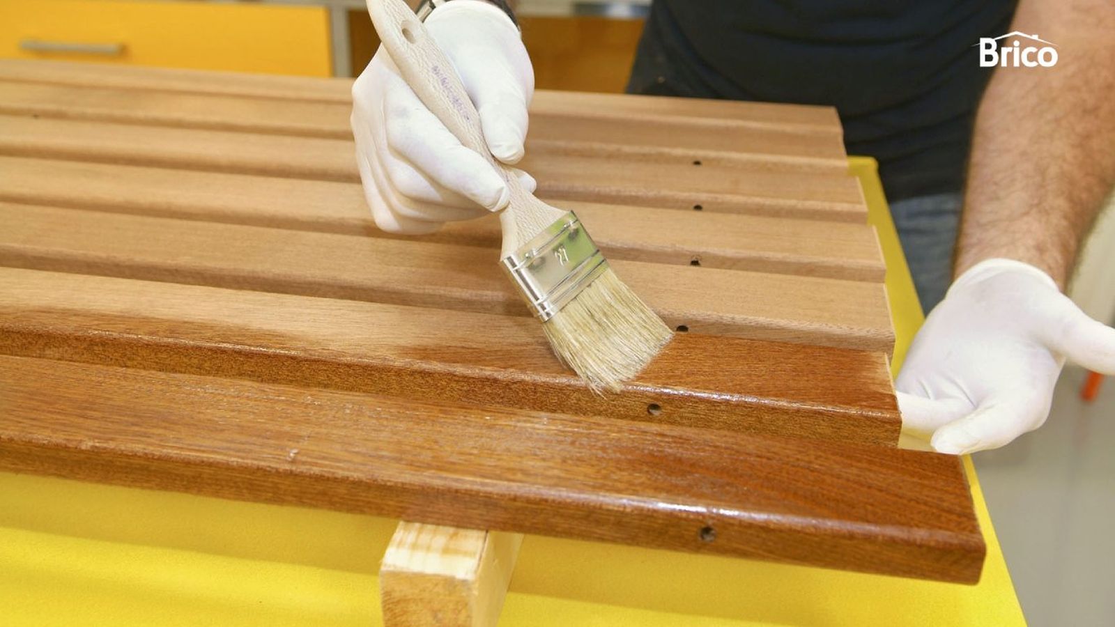 Persona aplica lasur en la madera