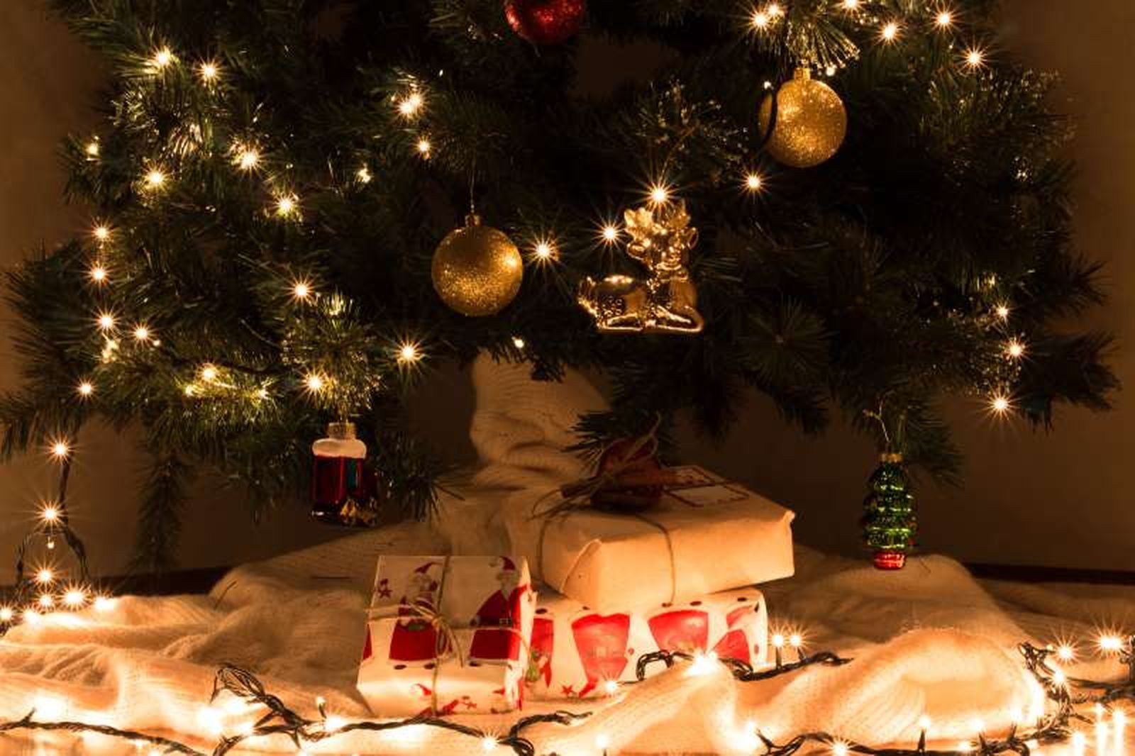 Pie del árbol de Navidad decorado con una manta y regalos.