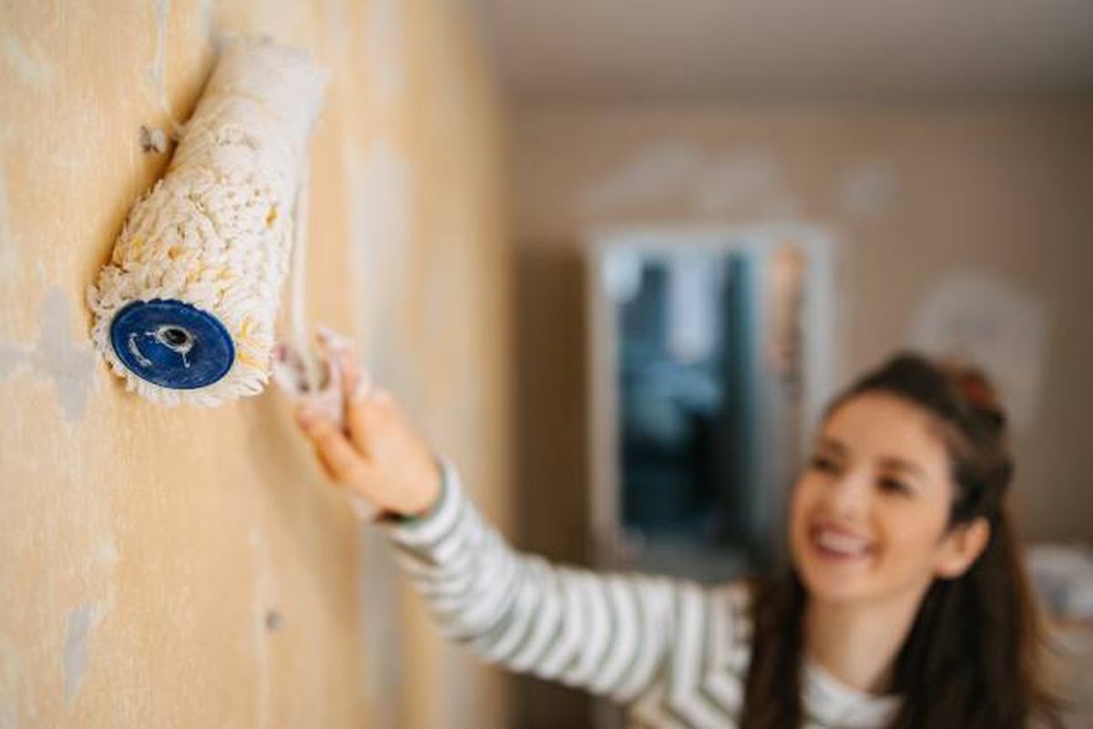 mujer pintando pared deteriorada