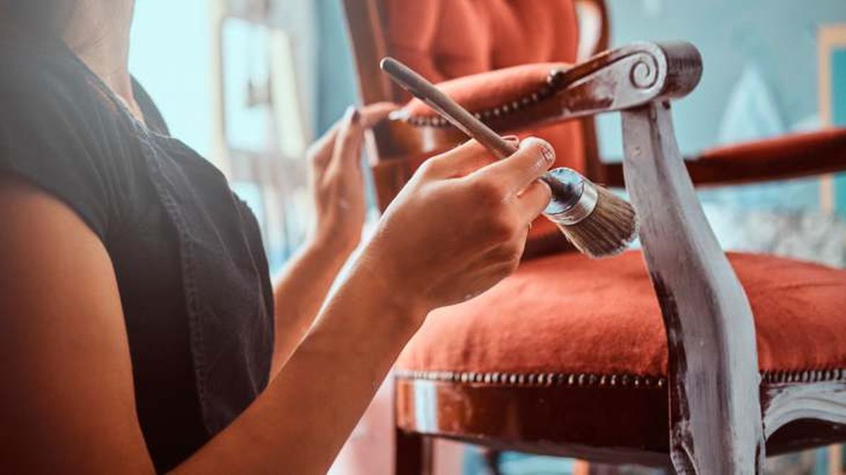 Persona pintando una silla de madera