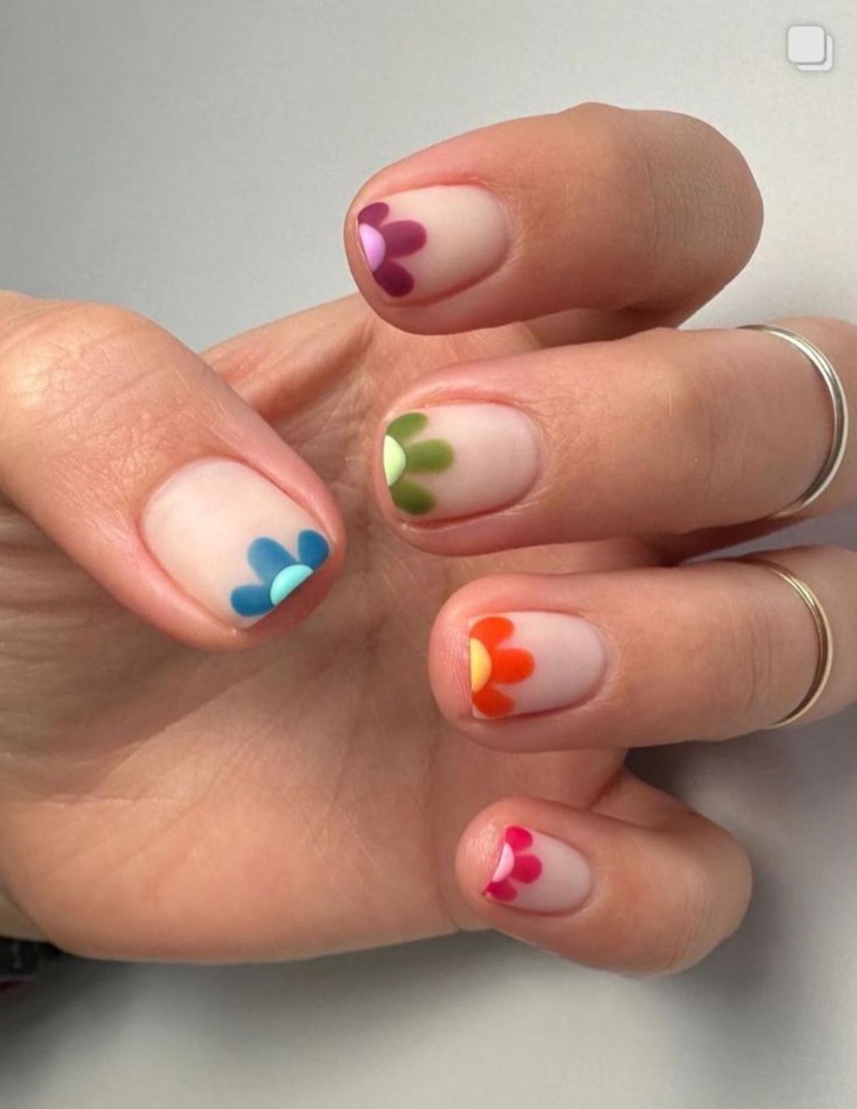 Uñas francesas con franja de flores de colores.