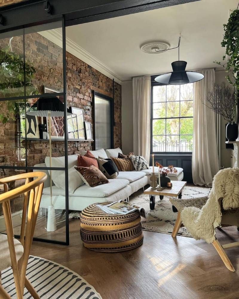 Salón de estilo industrial con sofá blanco y adornos modernos.