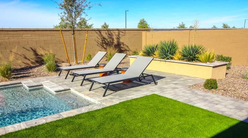 Patio con piscina y césped artificial.