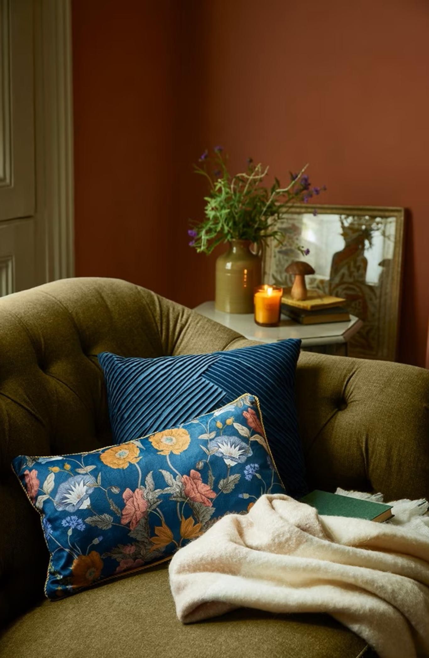 Sofá verde con cojines florales de estilo Cabincore.