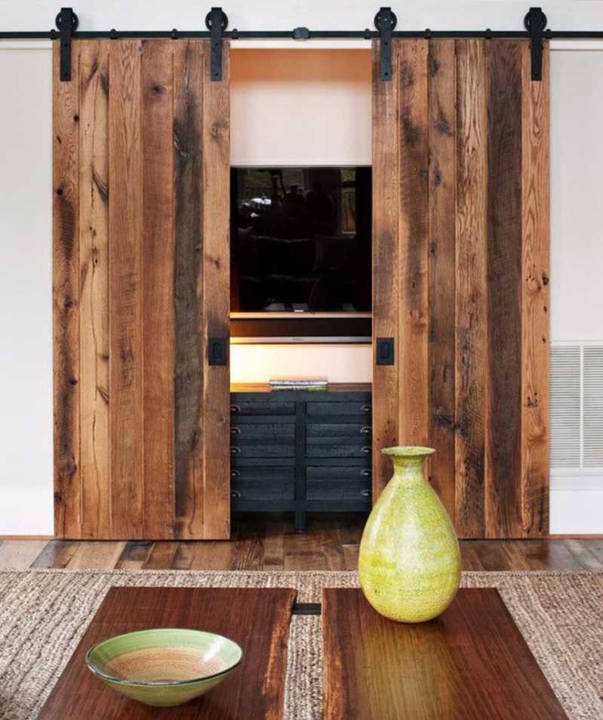Salón con armario con paneles verticales de madera para ocultar la televisión.